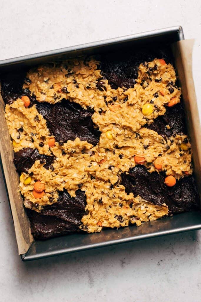 brownie batter and monster cookie dough in a baking pan