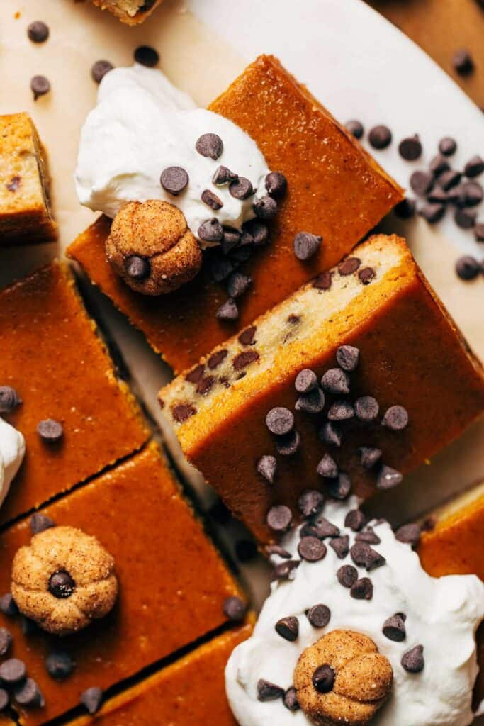 close up on slices of pumpkin pie bars baked with a chocolate chip cookie crust