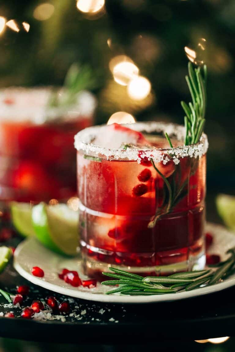 close up on a pomegranate margarita with a rosemary stem