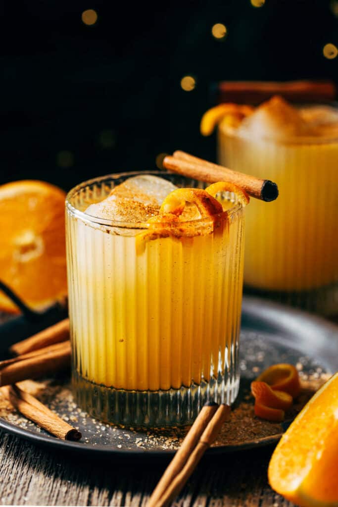 close up on an orange cocktail garnished with a cinnamon stick