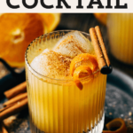 close up on an orange cocktail garnished with a cinnamon stick