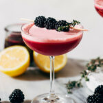 a vodka sour in a coupe glass and garnished with blackberries