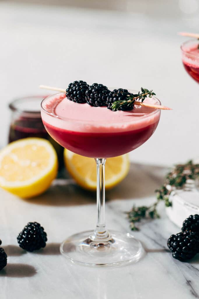 a vodka sour in a coupe glass and garnished with blackberries