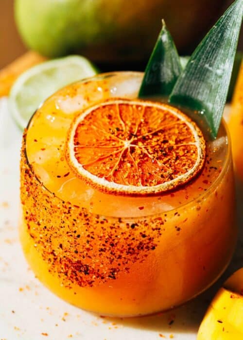 a mango margarita topped with a dehydrated orange slice