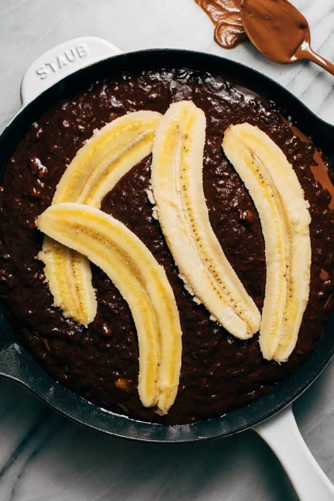 sliced bananas on top of chocolate banana cake batter