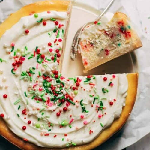 the top of a sliced sugar cookie cheesecake with frosting and sprinkles