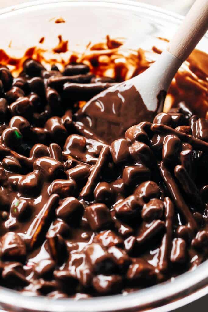 a bowl of melted chocolate mixed with marshmallows and pretzels