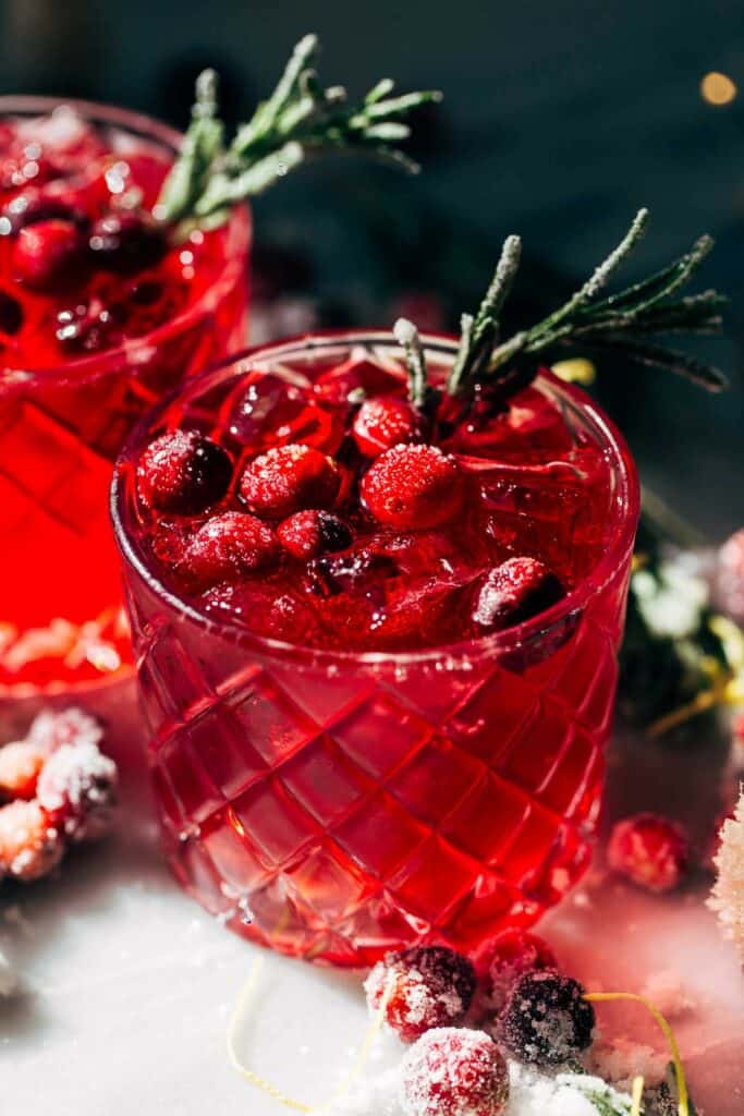 a cranberry limoncello spritz topped with cranberries and rosemary
