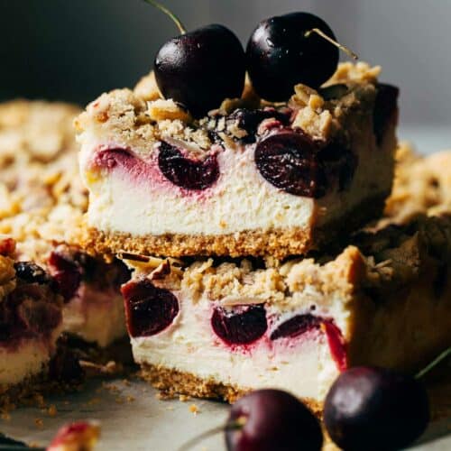 Close up of sliced cherry cheesecake bars, topped with two cherries