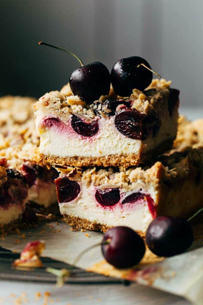 Close up of sliced cherry cheesecake bars, topped with two cherries