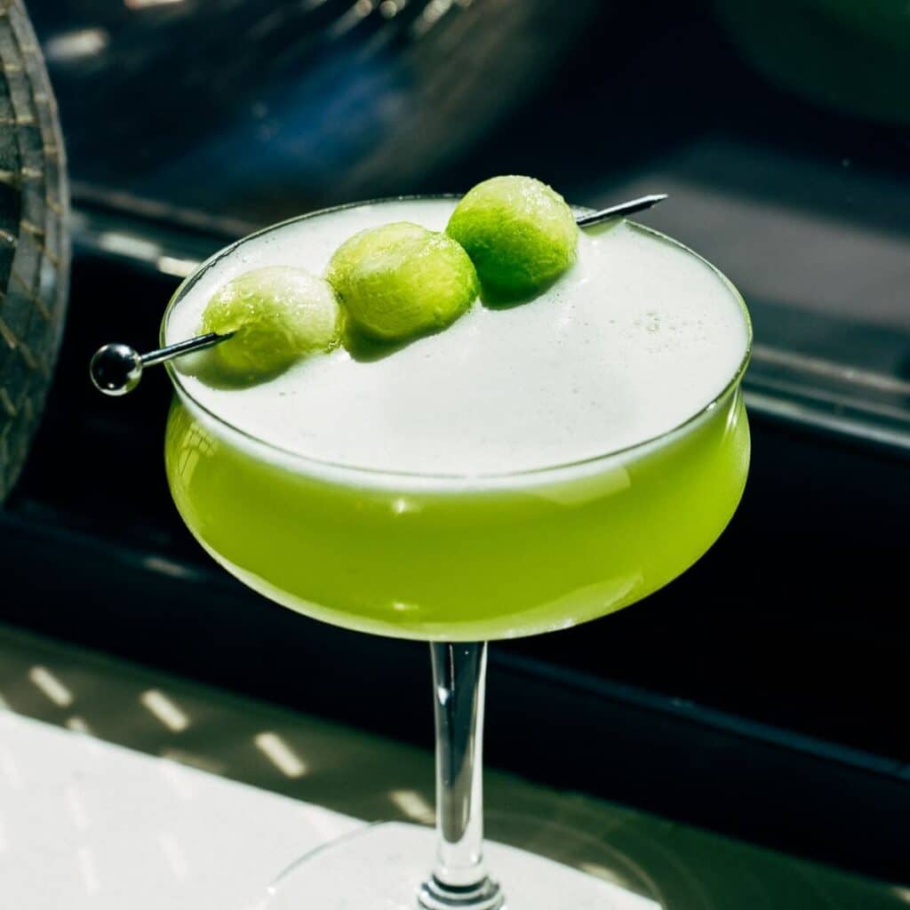 close up of honeydew tequila sour in a coupe glass