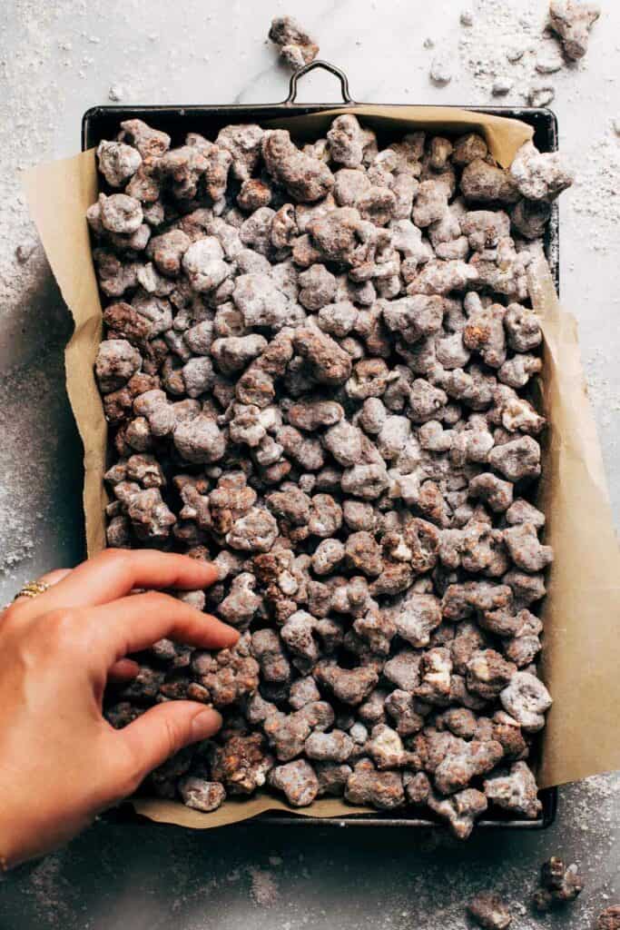 hand grabbing a handful of double chocolate popcorn puppy chow