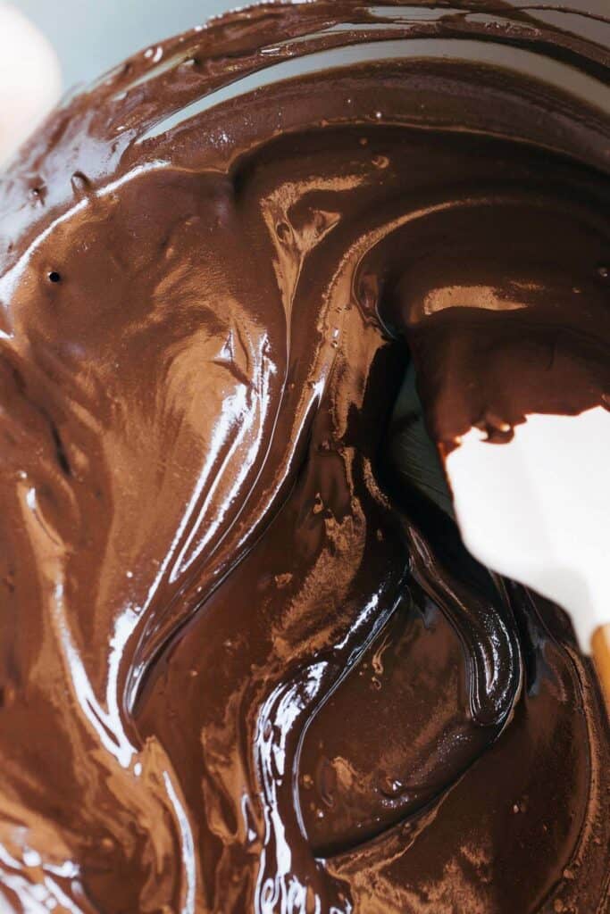 process shot of a rubber spatula stirring melted chocolate chips and sunbutter in a bowl