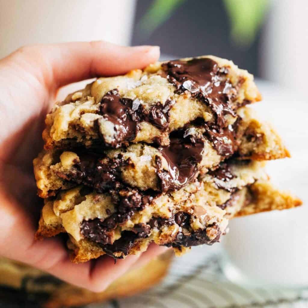 holding a stack of gooey bakery style chocolate chip cookies