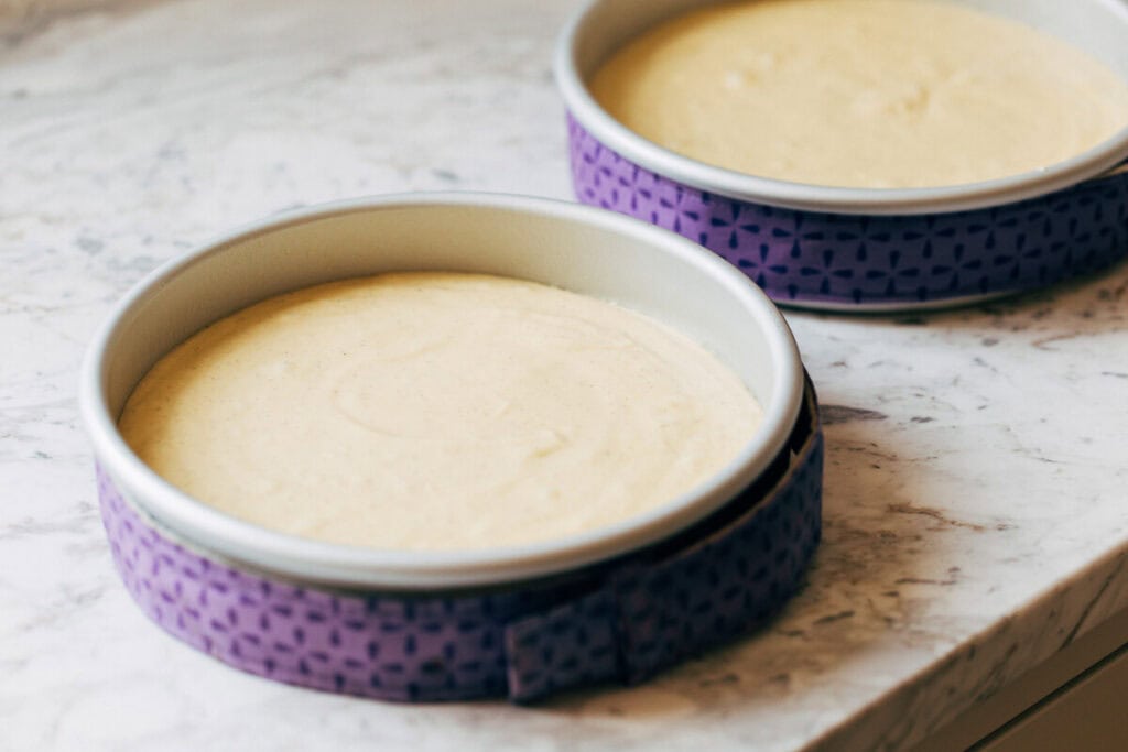 process shot of cake batter in baking pans with a cake strip