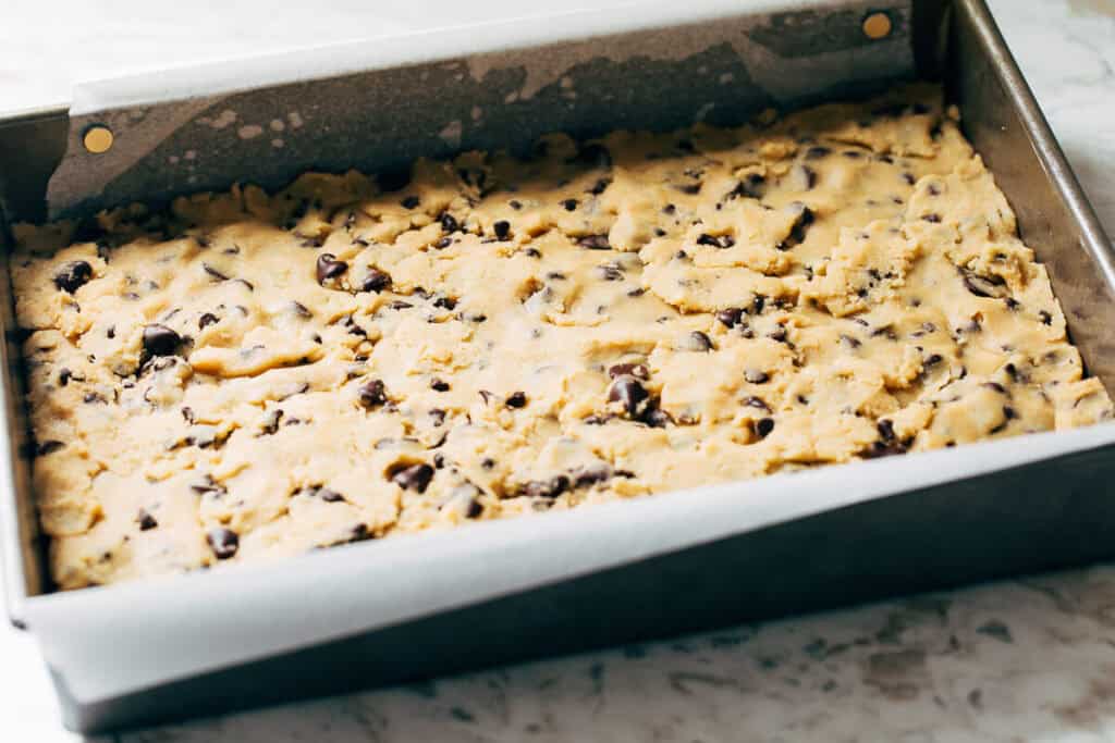 process shot of cookie dough layer in a pan