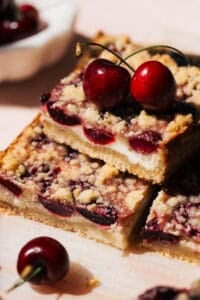 a stack of cheesecake bars baked with a layer of fresh cherries
