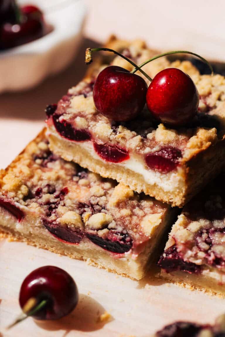 a stack of cheesecake bars baked with a layer of fresh cherries
