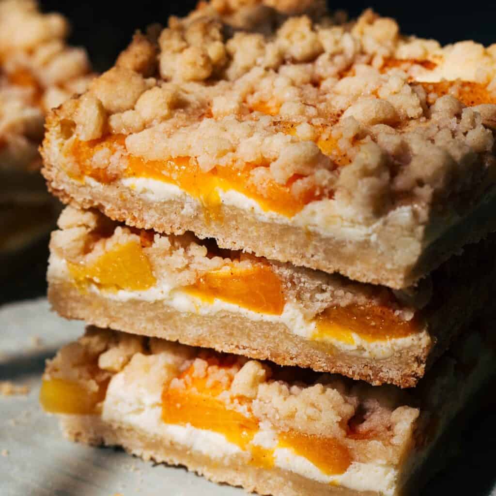 close up on stacked peach cheesecake bars
